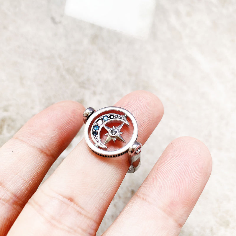 O elemento movél de lua e estrela no centro é o destaque deste anel de sinete altamente detalhado, feito de prata de lei com banho de ródio branco.  Ele gira em torno de seu próprio eixo, é desenhado com recortes e adornado com pedras vitrocerâmicas, espinélio sintético e pedras de zircônia.  Decida por si mesmo e escolha o lado que você quer usar. Cravejado ou liso.